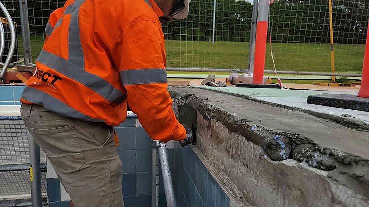 Crew member correcting a concrete edge near an opening