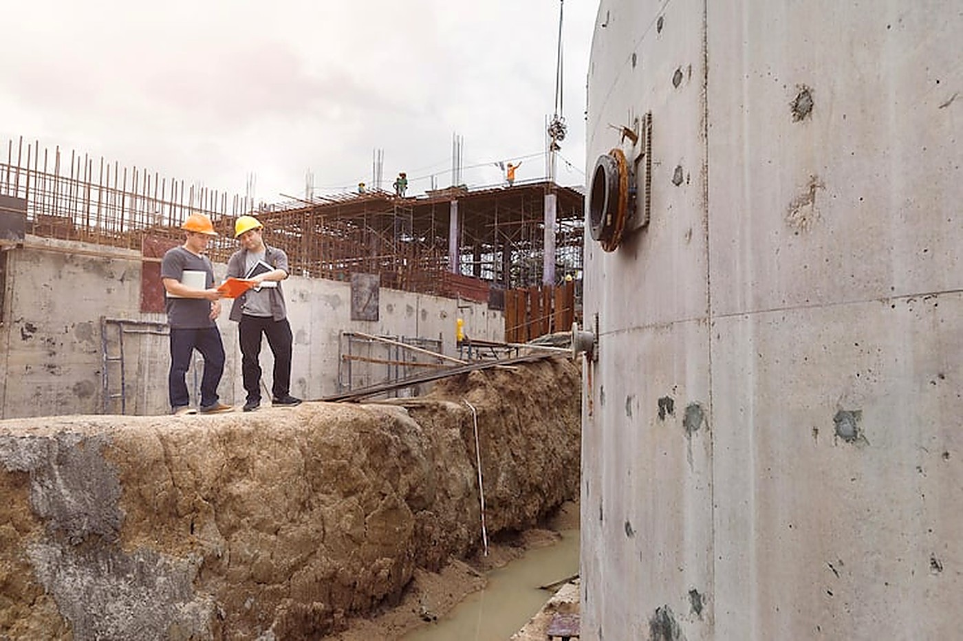 Site engineers reviewing plans beside a concrete structure