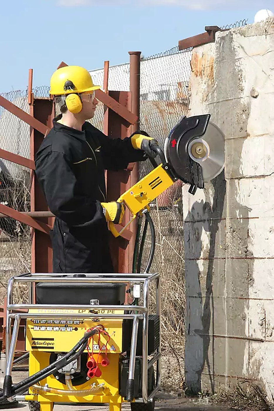 Technician cutting a reinforced concrete wall with a hydraulic disc saw
