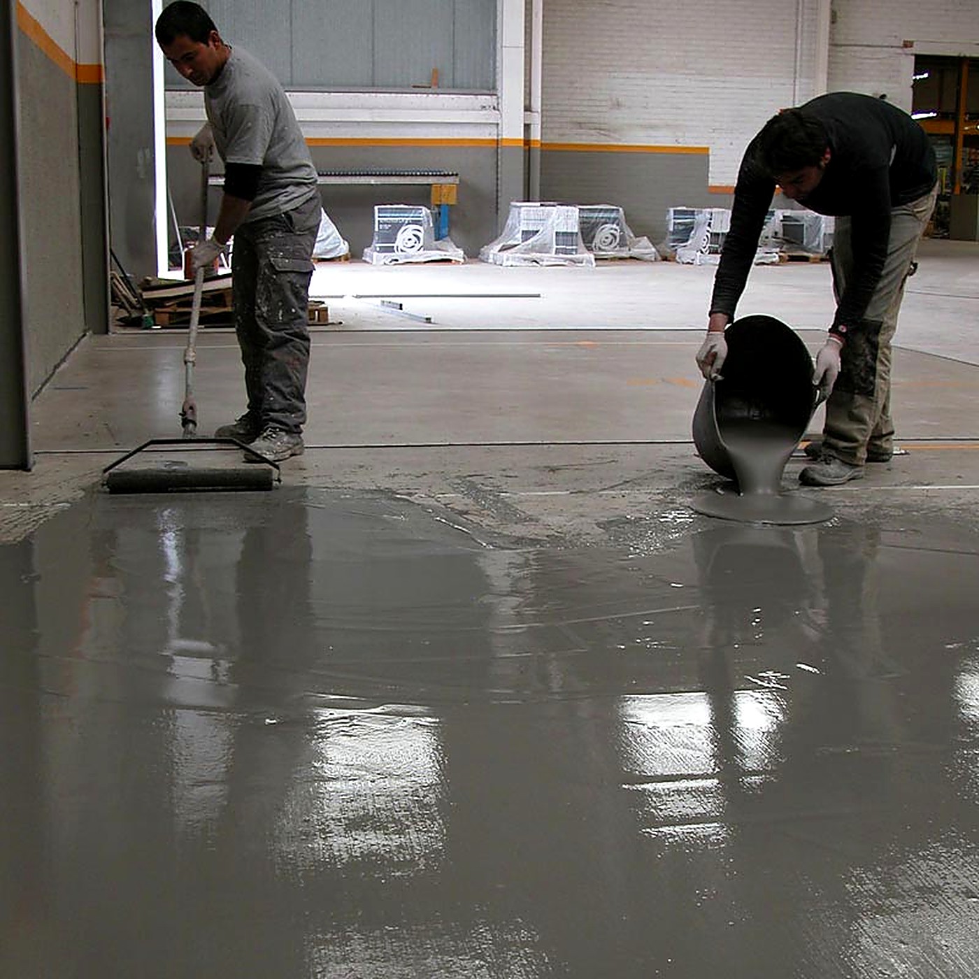 Crew pouring and spreading self-leveling compound on a concrete floor